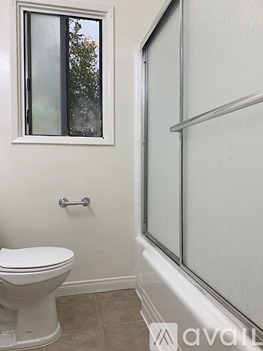 A white toilet sits in a bathroom next to a window.