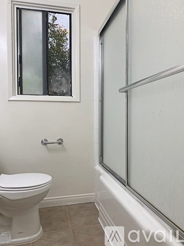 A white toilet sits in a bathroom next to a window.