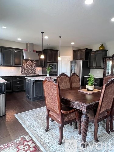 A kitchen with a table and chairs in the foreground and a refrigerator in the background.