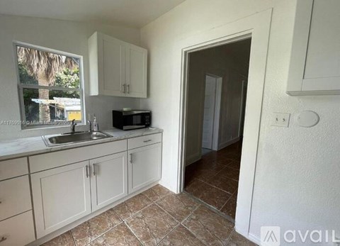 A kitchen with white cabinets and a tiled floor.