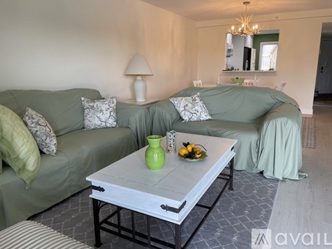 A living room with two green couches and a coffee table with a green vase on it.