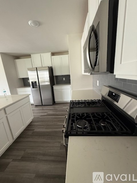 A kitchen with white cabinets and a black stove top.