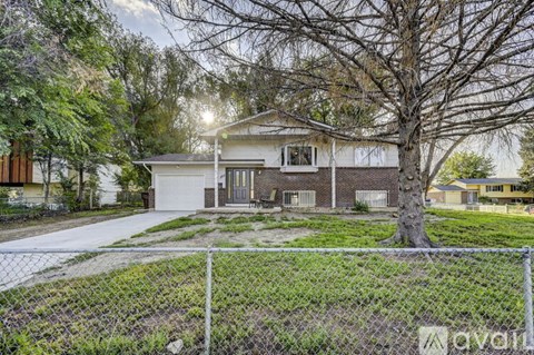 A house with a white fence and a tree in front.