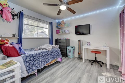 A bedroom with a bed, desk, and ceiling fan.