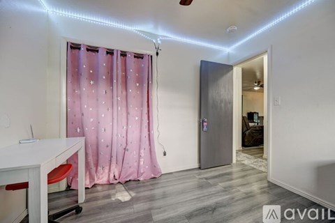 A room with a pink curtain and a white desk.