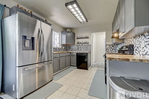 A kitchen with a stainless steel refrigerator and a black and white tiled backsplash.
