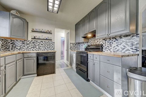 A kitchen with grey cabinets and a black and white checkered backsplash.