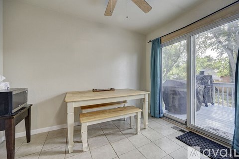 A room with a table and a bench in front of a sliding glass door.