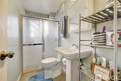 A bathroom with a toilet, sink, and shower.