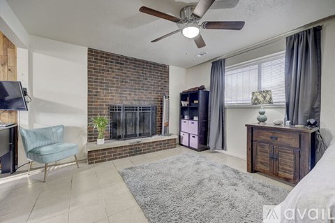 A living room with a brick fireplace and a grey rug.