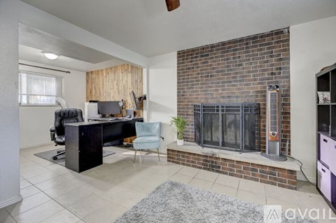 A modern living room with a brick fireplace and a black desk.