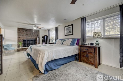 A bedroom with a bed, dresser, and a fireplace.
