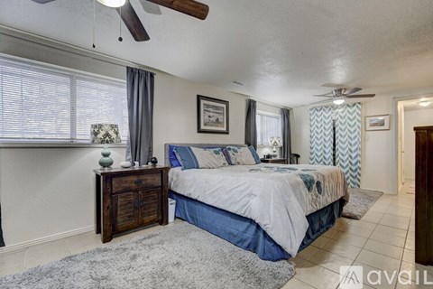 A bedroom with a bed, dresser, and ceiling fan.