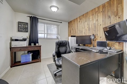 A room with a desk, chair, and computer setup.
