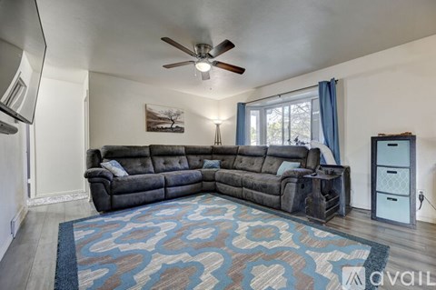 A living room with a large sectional sofa and a rug.