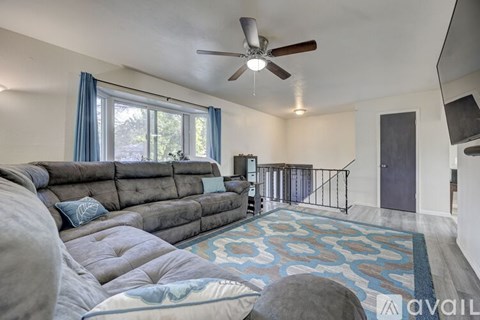 A living room with a grey couch and a ceiling fan.