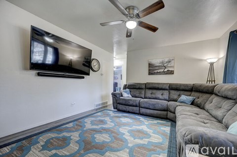 A living room with a grey couch and a flat screen TV mounted on the wall.