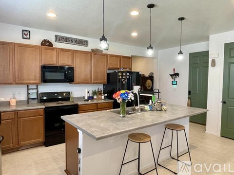A kitchen with wooden cabinets and a large island with bar stools.