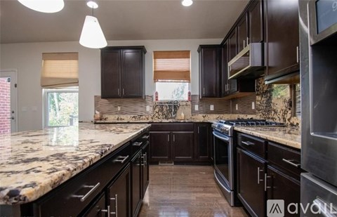 A kitchen with dark brown cabinets and granite countertops.