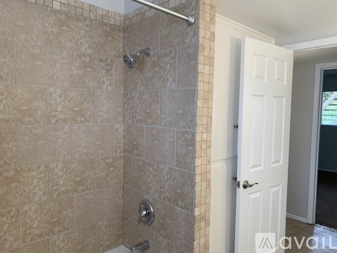 A bathroom with a tiled shower and a white door.