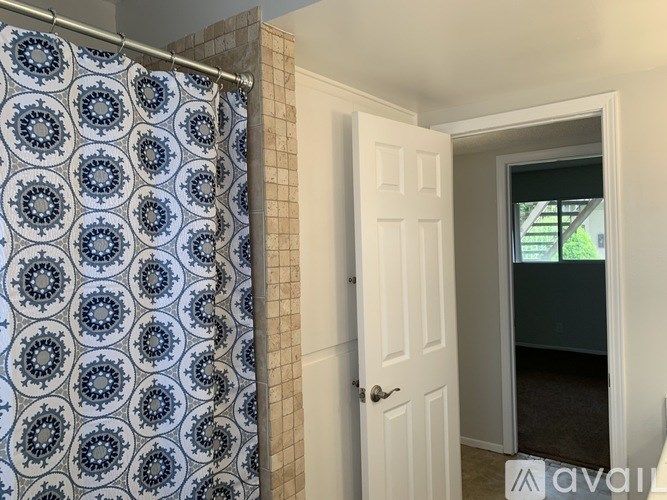 A bathroom with a blue and white shower curtain and a white door.