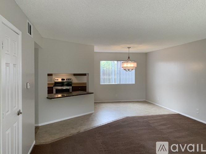 A room with a brown carpet and a hanging light fixture.