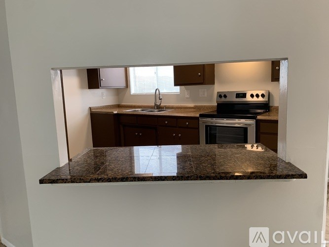 A kitchen with a granite countertop and wooden cabinets.