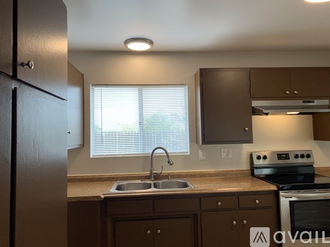 A kitchen with a sink, stove, and cabinets.