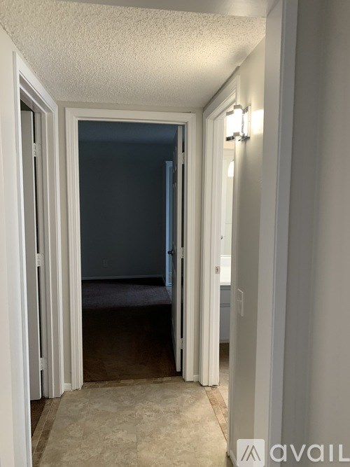 A hallway with a carpeted floor and white walls.