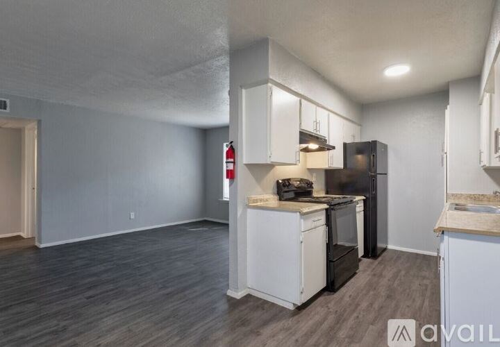 A kitchen with white cabinets and a black fridge.