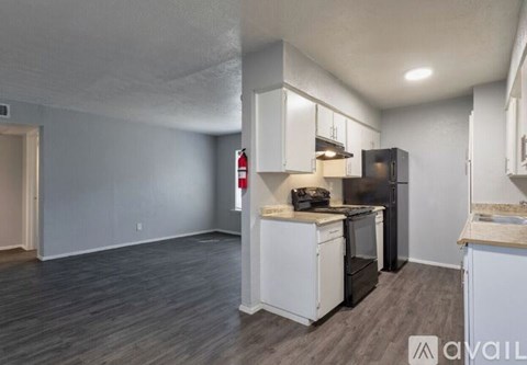 A kitchen with white cabinets and a black fridge.