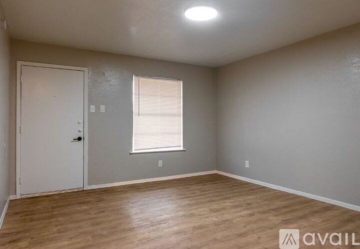 A room with wooden flooring and a window with blinds.