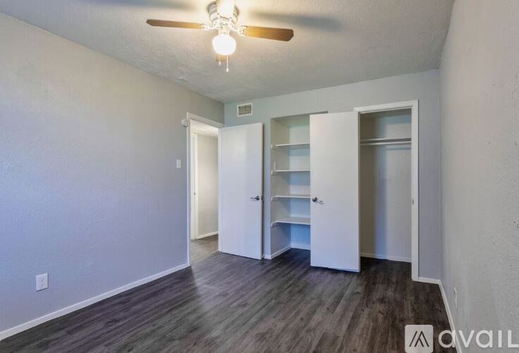 A room with a ceiling fan and wooden flooring.
