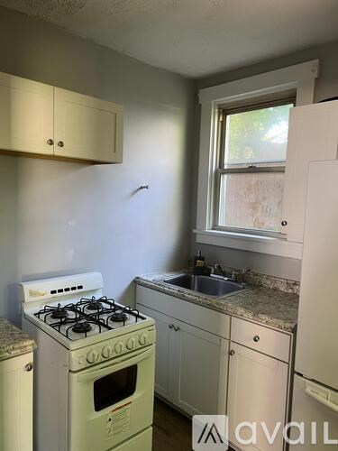 A small kitchen with a white stove and cabinets.