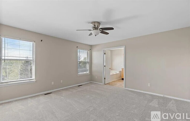 A spacious room with a ceiling fan and a doorway leading to another room.