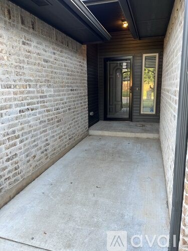 A hallway with a brick wall and a door.