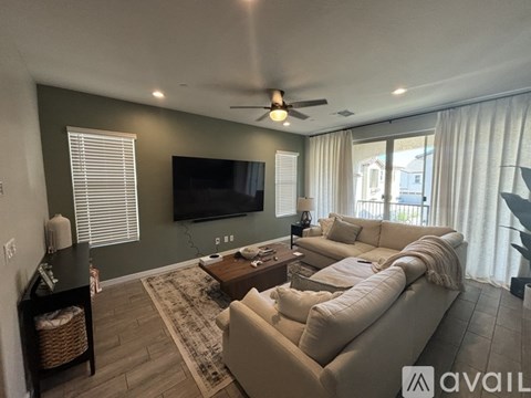 A living room with a television, a couch, and a ceiling fan.