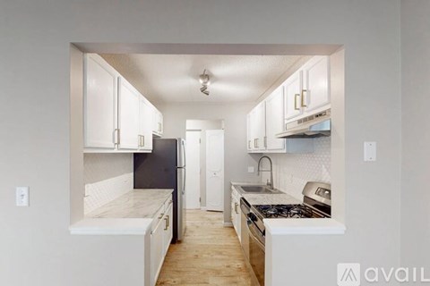 A kitchen with white cabinets and a black fridge.