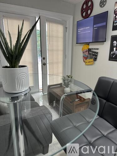 A living room with a grey couch, a glass table, and a television mounted on the wall.