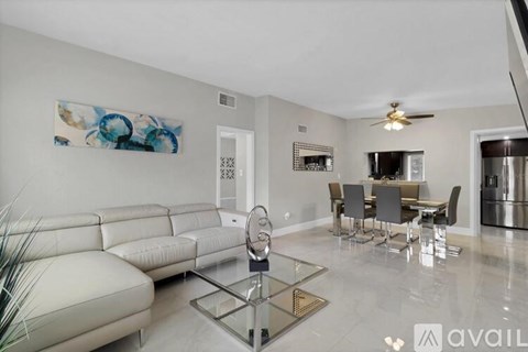 A modern living room with a glass coffee table and a white sofa.