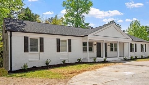 A white house with a black roof and a grey front porch.