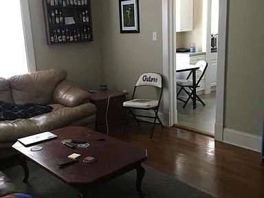 A living room with a brown leather couch, a wooden coffee table, and a chair with the word "Gators" on it.