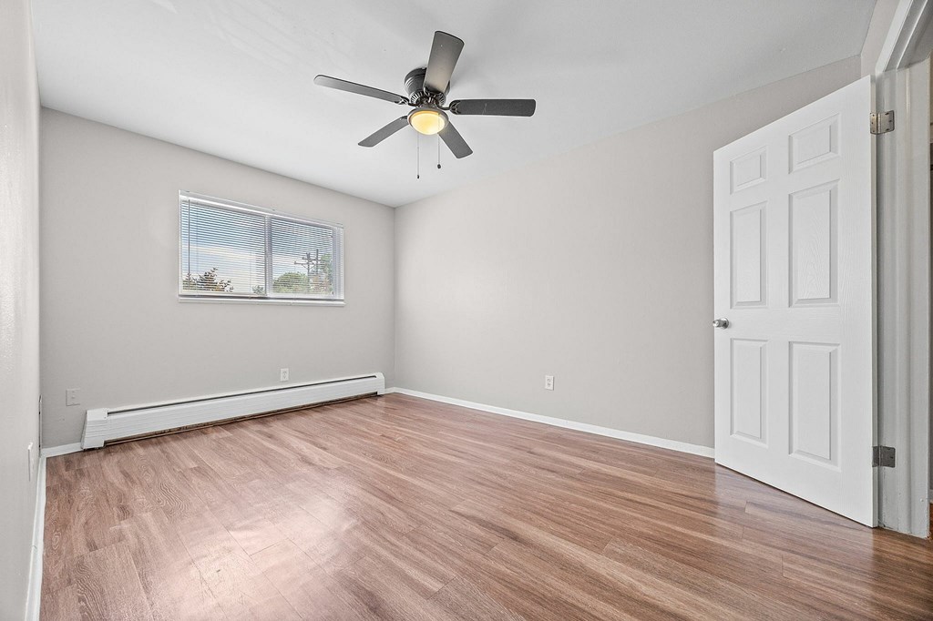 A room with a ceiling fan and a window with blinds.
