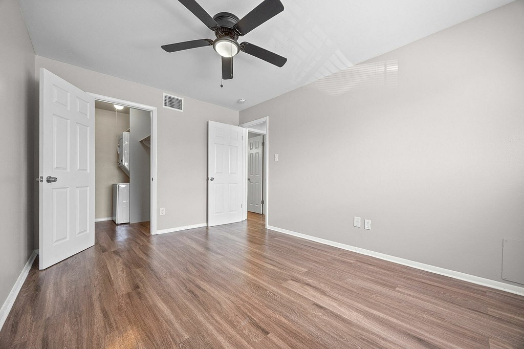 A room with a ceiling fan and wood flooring.