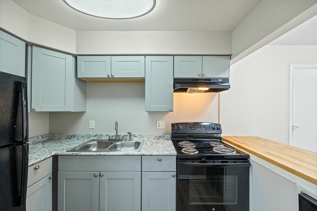 A kitchen with a black stove top oven and a black refrigerator.