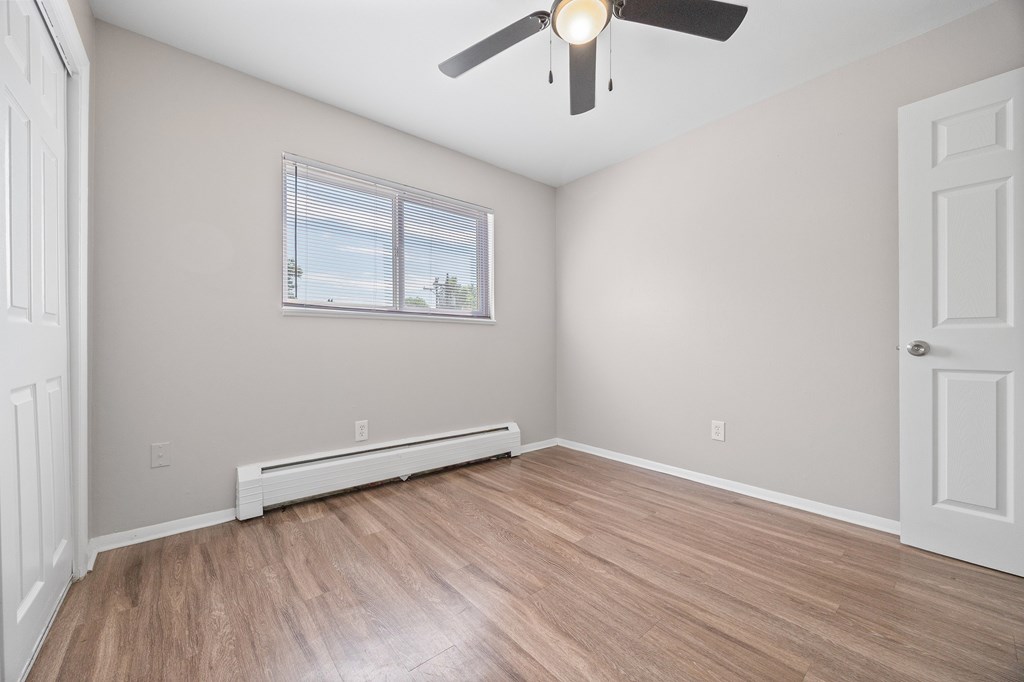 A room with a ceiling fan and a window with blinds.