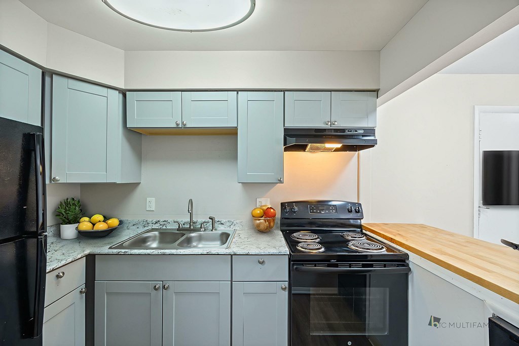 A kitchen with a black stove top oven and a black refrigerator.