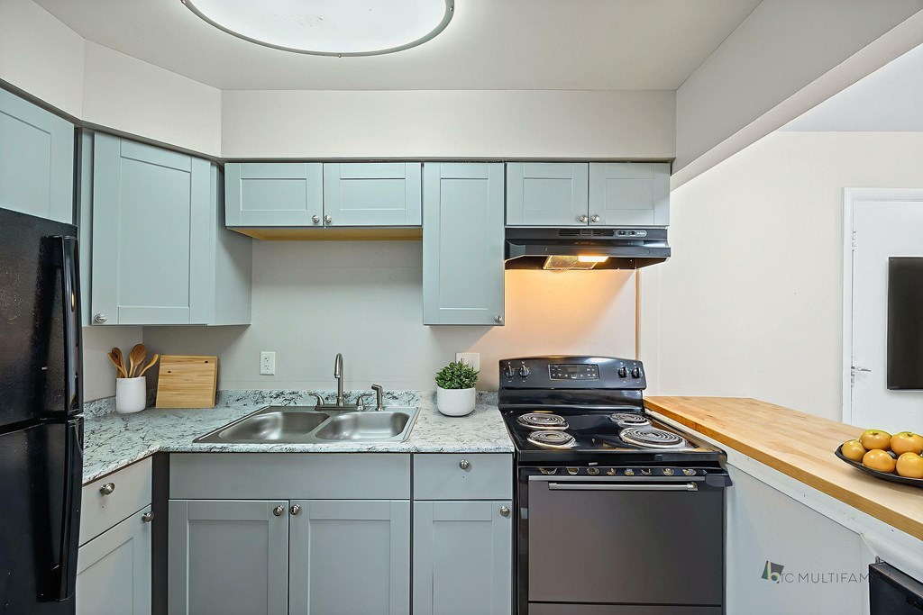 A kitchen with a black refrigerator, a black stove, and a black oven.