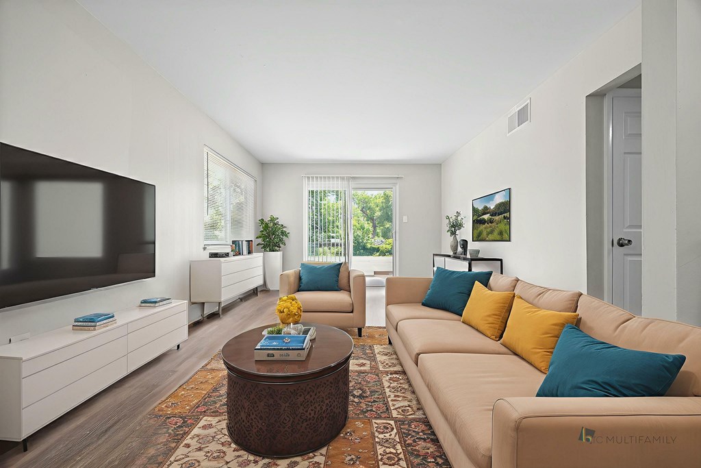 A living room with a brown coffee table and a beige couch with blue and yellow pillows.