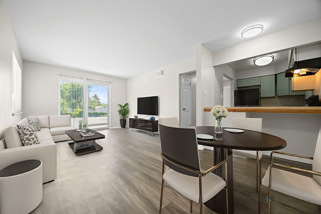A modern living room with a white sofa, a black chair, and a wooden dining table.